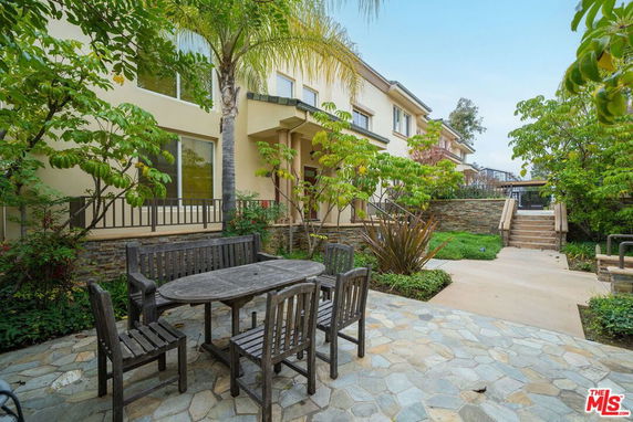 Front view of a two-story house with stone pathway and outdoor seating area.