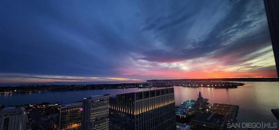Panoramic view of cityscape and coastline at sunset.