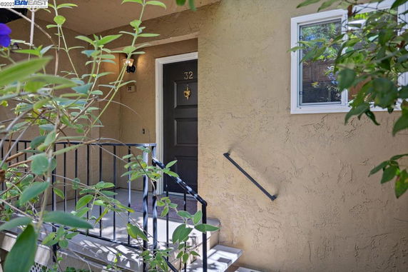 Front view of a house entrance with a dark door, railing, and window.