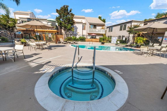 Outdoor area featuring a swimming pool and seating with umbrellas.