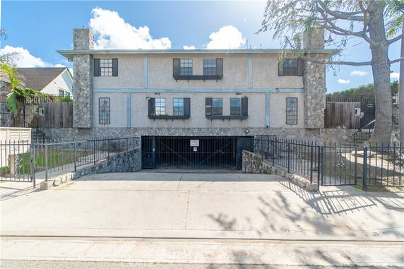 Front view of a two-story house with stone and stucco exterior, featuring multiple windows and a garage entrance.