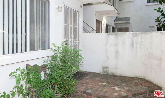 Front view of a residential building entrance with a brick pathway and metal gate.