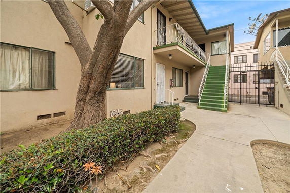 View of a two-story residential building with an external staircase and a small courtyard area.