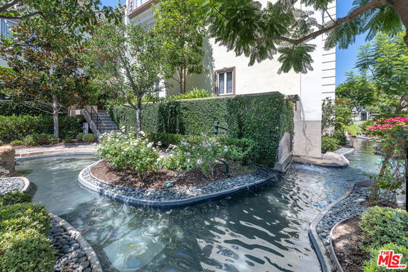 Exterior view of a building with water features and lush greenery.