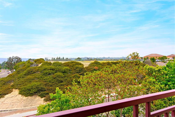 Panoramic view from a building overlooking hilly terrain and distant structures.