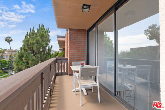 Balcony with outdoor seating overlooking surrounding area.