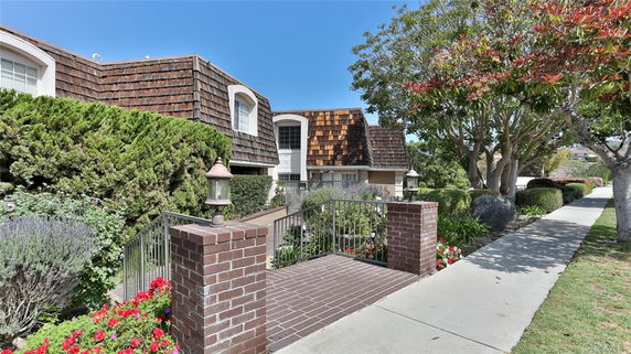 Front view of a house with wood shingle exterior and brick walkway.