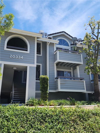 Front view of a multi-story house with balconies and arched windows.
