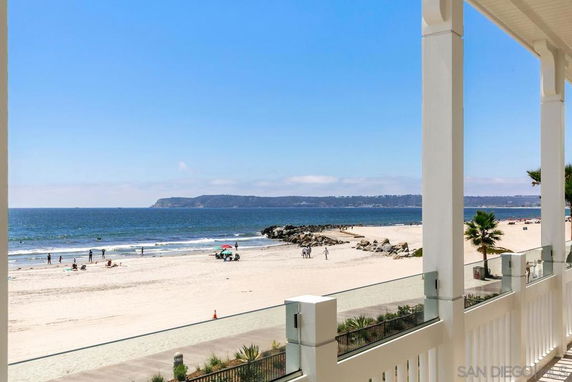View of a beach and ocean from a building balcony.