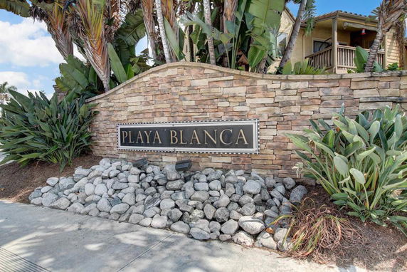 Front view of a building with stone facade and tropical plants.