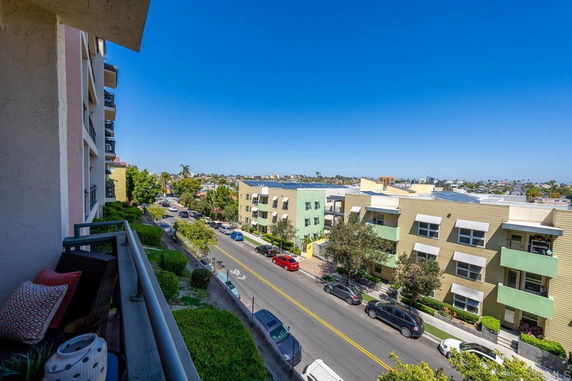 Panoramic view from a building showing a street lined with buildings and cars, under a clear blue sky.