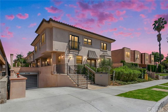 Front view of a two-story house with a staircase leading to the entrance and a garage on the lower level.