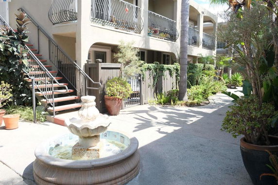 Front view of a two-story building with exterior stairs and a decorative fountain.