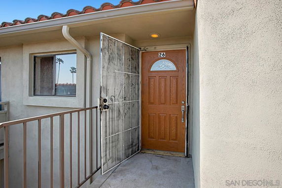 Front view of a house with a single wooden door and security gate.