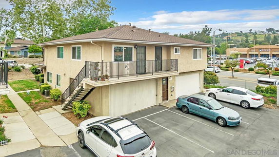 Front view of a two-story building with external staircase and garage.