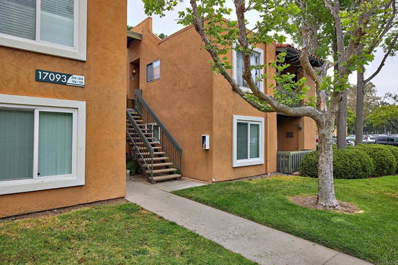 Front view of an apartment building with exterior stairs and orange stucco facade.
