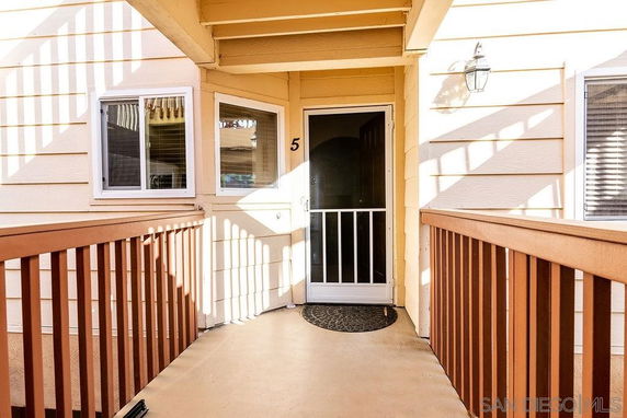 Front view of a house entryway with a wooden railing and screened door.