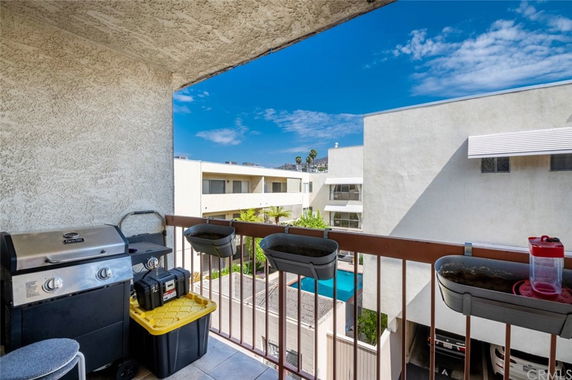 Balcony view showing adjacent buildings and a swimming pool.