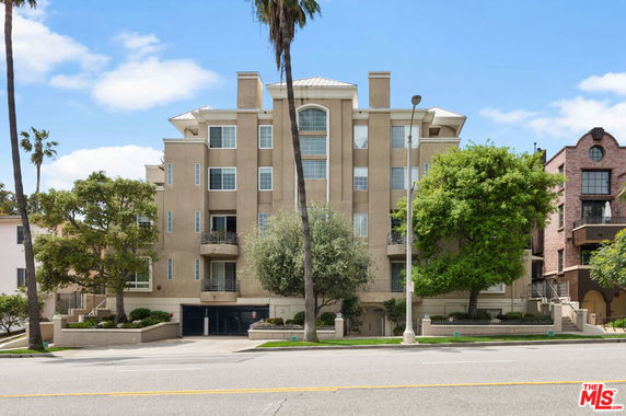 Front view of a multi-story residential building with balconies and a gated entry.