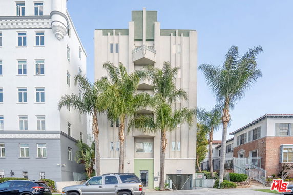 Front view of a multi-story building with palm trees in front.