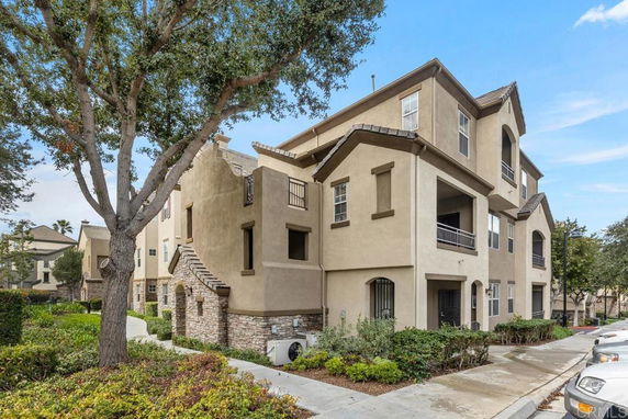 Front view of a multi-story residential building with balconies and stone accents.