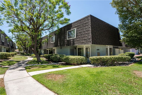 Front view of a two-story townhouse with a dark shingled roof and beige exterior.
