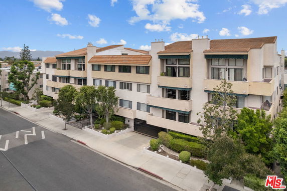 Front view of a multi-story building with balconies and a sloped roof.