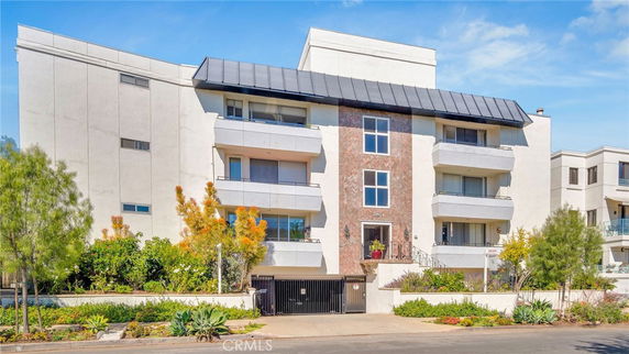 Front view of a multi-story apartment building with balconies and a central entrance.