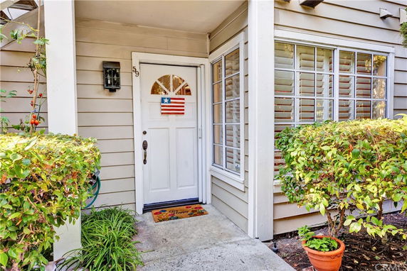 Front view of a corner entrance to a house with a white door and adjacent windows.