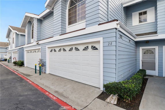 Front view of a townhouse with a double garage and an entry door on the right side.