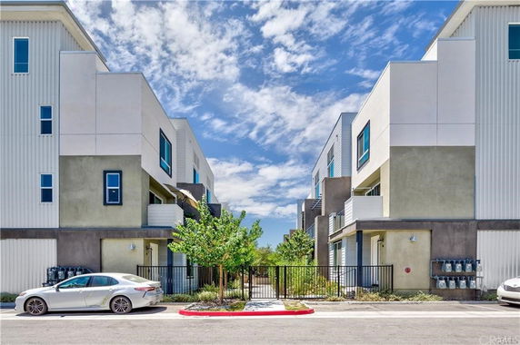 Front view of a modern multi-story building with large windows and a gated entrance.