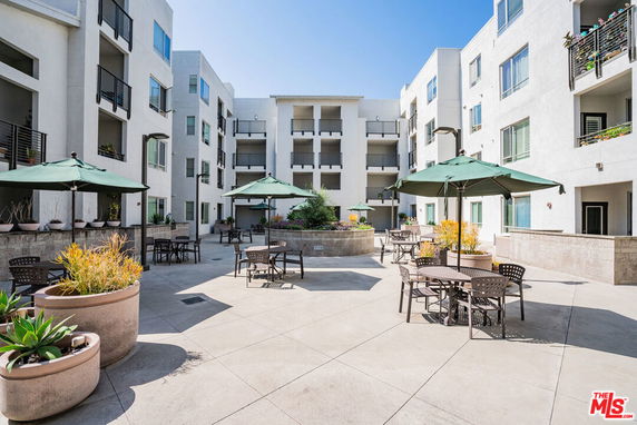 Courtyard view of a multi-story residential building with balconies and outdoor seating.