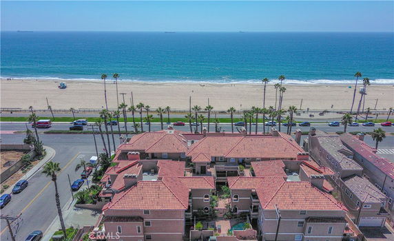 Aerial view of beachfront buildings with a road and beach in the background.
