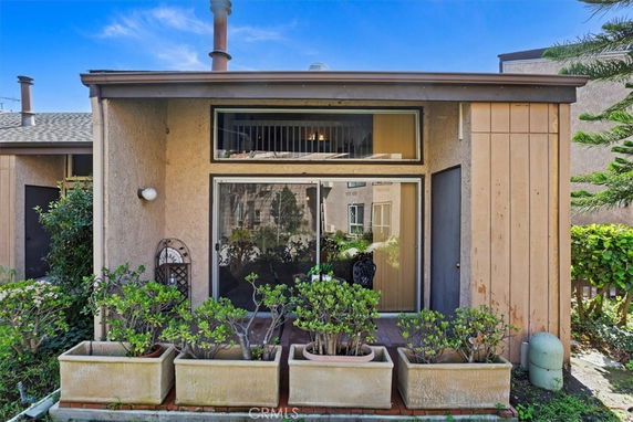 Front view of a small house with large windows and potted plants.