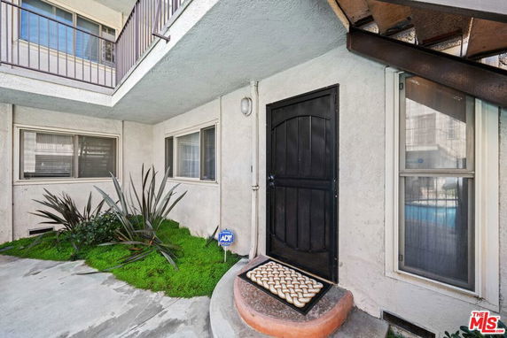 Entrance view of a residential building with a black door and windows.