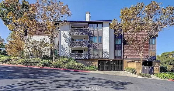 Front view of a multi-story apartment building with balconies and a gated entrance.