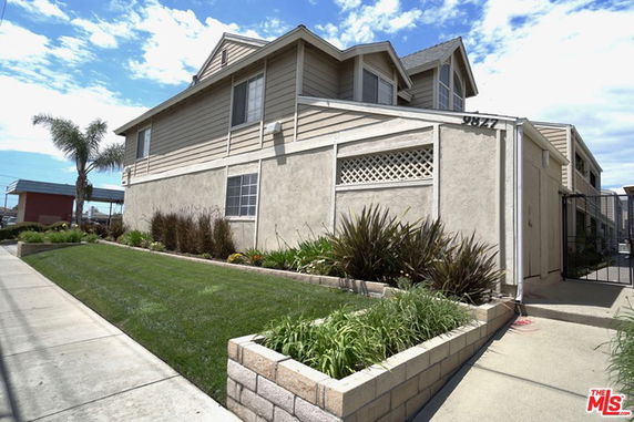Front view of a two-story house with a well-maintained garden and a side entrance.