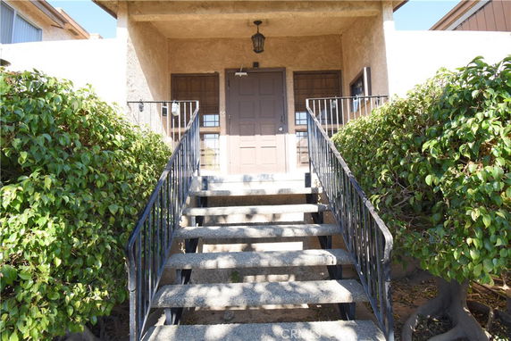 Front view of a building entrance with a staircase and railing.