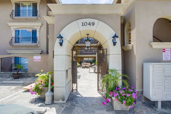 Front view of a building entrance with an arched gateway and decorative plants.