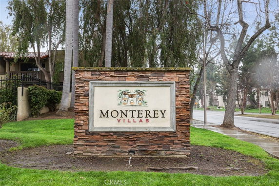 Front view of Monterey Villas with a stone sign and surrounding greenery.