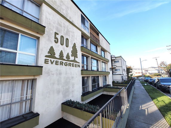 Front view of a multi-story apartment building with the name 'Evergreen' displayed on the wall.