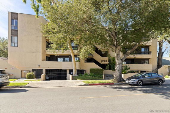 Front view of a multi-story apartment building with trees in the foreground.