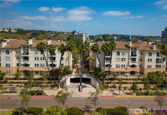 Front view of a multi-story residential building with palm trees in front.