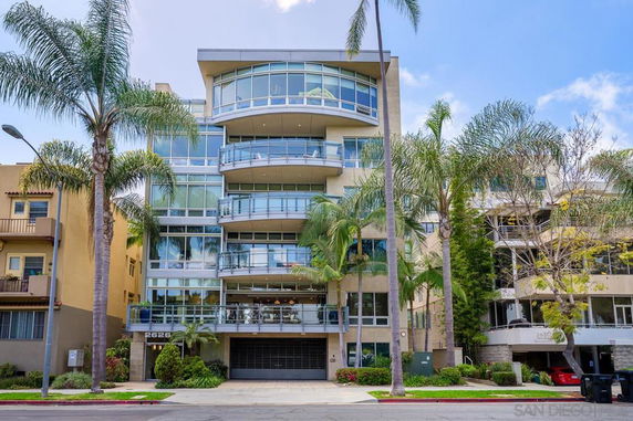 Front view of a modern multi-story building with balconies and large glass windows.