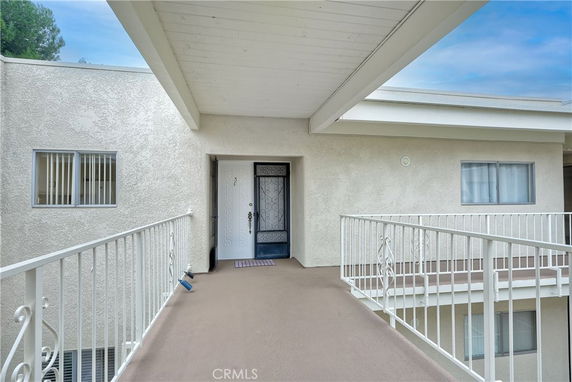 Front view of an apartment entrance with a walkway and metal railing.
