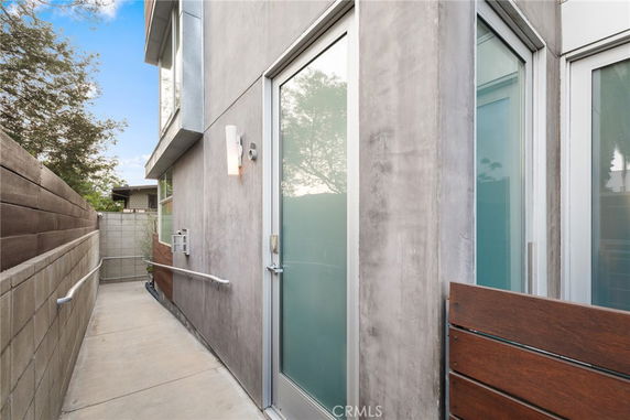 Side view of a modern building with glass doors and concrete walls.