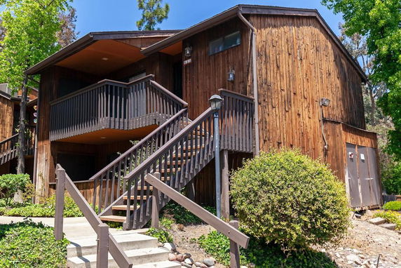 Front view of a wooden multi-story building with an external staircase and balcony.