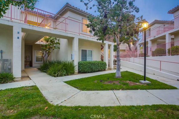 Front view of a two-story apartment building with balconies and a walkway.
