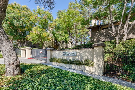 Front view of a gated residential entrance with a sign and trees.