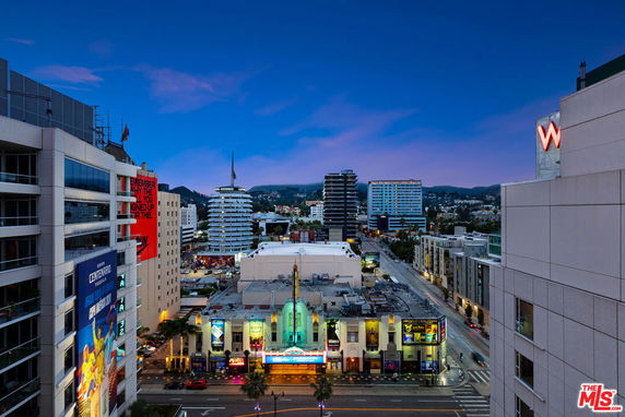 Panoramic view of a cityscape featuring a street with multiple buildings and signage in the evening.